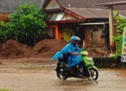 pengendara motor melintas di jalan tergenang saat hujan di sulawesi selatan