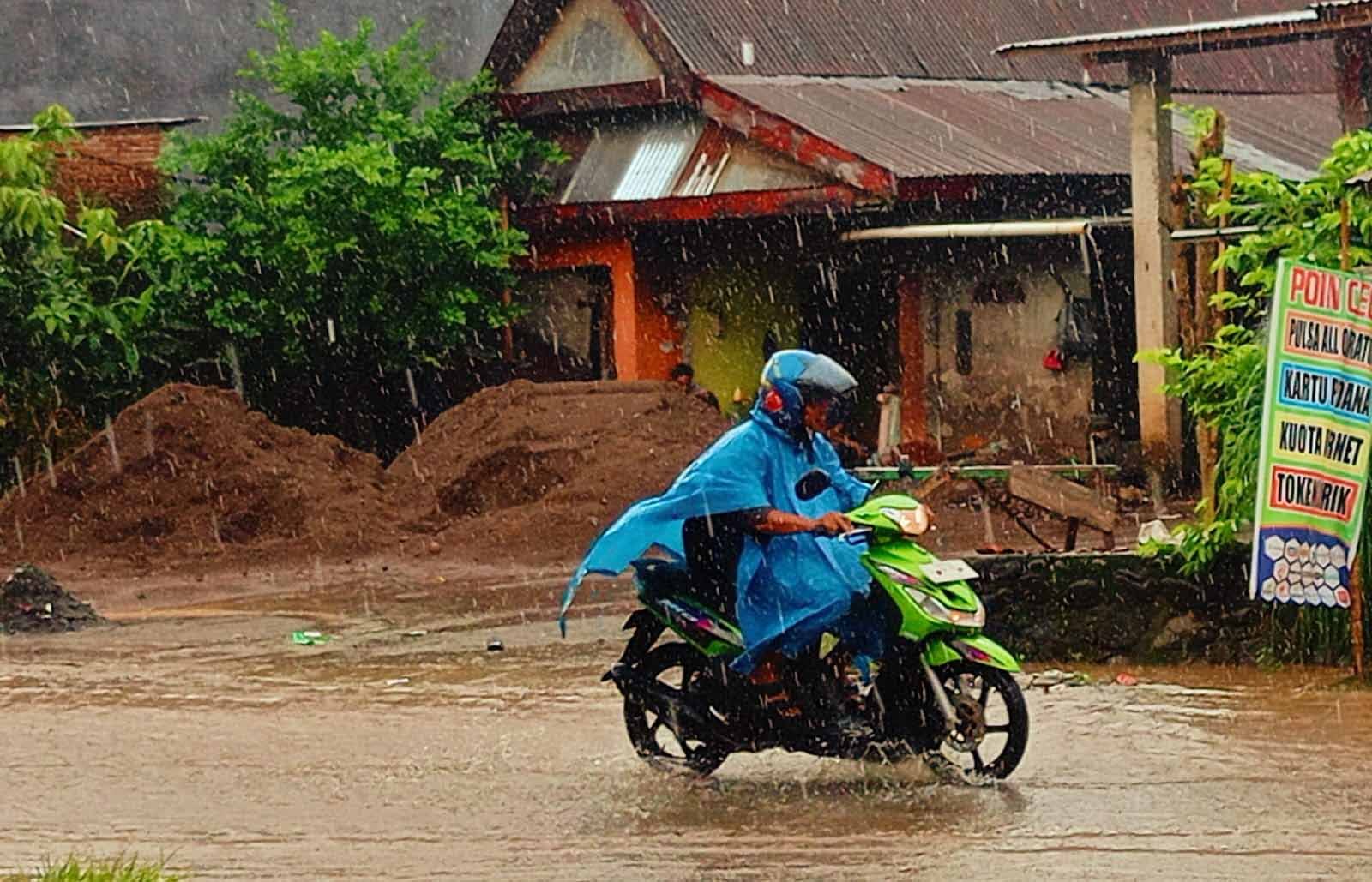 pengendara motor melintas di jalan tergenang saat hujan di sulawesi selatan