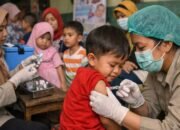 petugas kesehatan memberikan imunisasi campak kepada anak di fasilitas kesehatan
