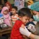petugas kesehatan memberikan imunisasi campak kepada anak di fasilitas kesehatan