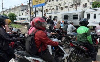 Pengendara motor menunggu di perlintasan sebidang saat kereta melintas di Bekasi Timur