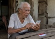 Warga mengecek rincian bantuan PKH 2026 melalui ponsel dan Kartu Keluarga Sejahtera