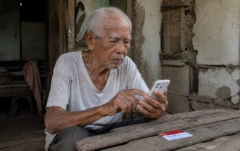 Warga mengecek rincian bantuan PKH 2026 melalui ponsel dan Kartu Keluarga Sejahtera