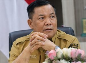 Plt Gubernur Riau SF Hariyanto mengenakan seragam dinas dengan latar bendera Indonesia.