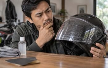 Pengendara memeriksa baret pada visor helm sebelum melakukan perawatan atau pemolesan.
