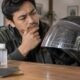 Pengendara memeriksa baret pada visor helm sebelum melakukan perawatan atau pemolesan.