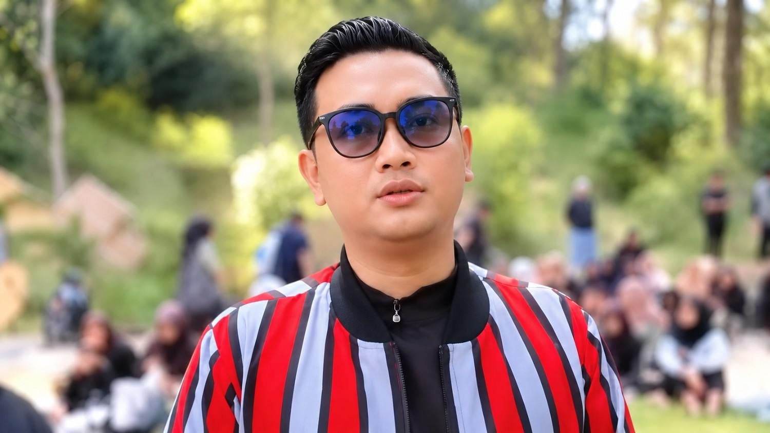 Bupati Klaten Hamenang Wajar Ismoyo mengenakan kacamata hitam dan jaket bergaris merah saat berada di luar ruangan.