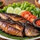 Ikan asap matang yang disajikan bersama sayuran sebagai ilustrasi cara aman mengonsumsi ikan asap.